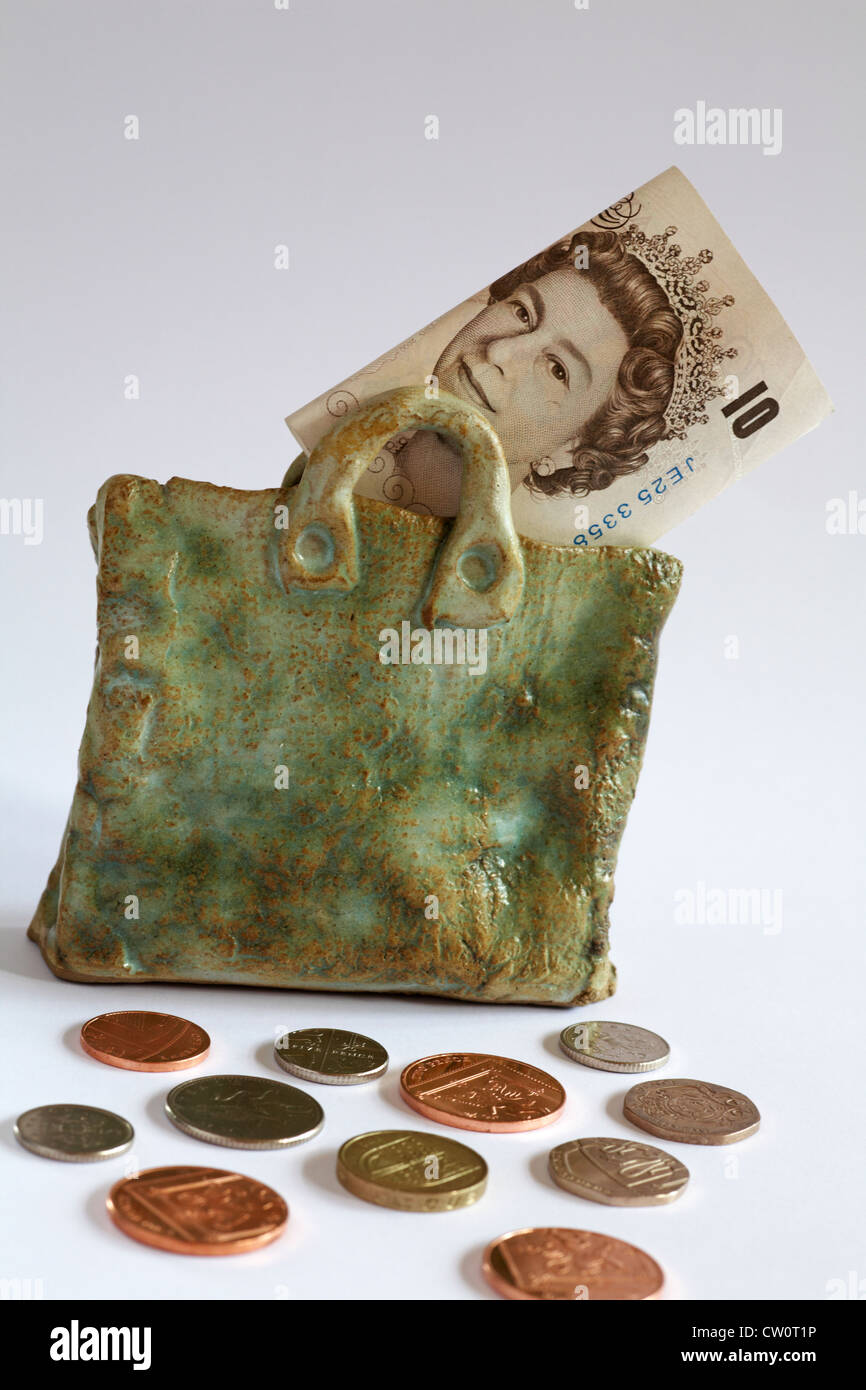 Money bag - £10 note showing Queen's head in pottery bag with coins spread around isolated on white background Stock Photo