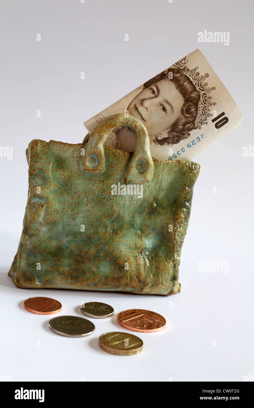 Money bag - £10 note showing Queen's head in pottery bag with coins spread around isolated on white background Stock Photo