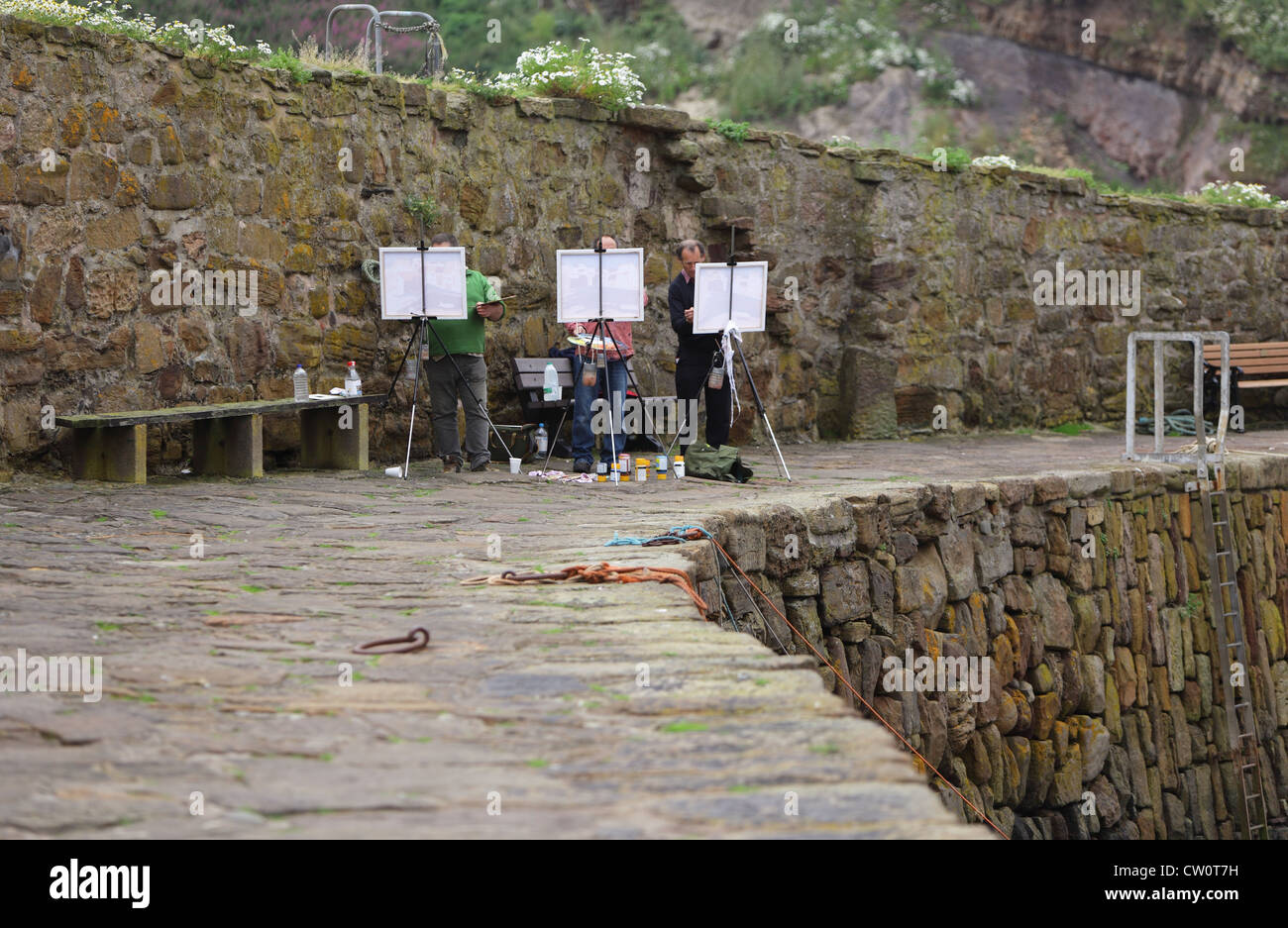 Three Artists painting in Crail Harbour Stock Photo
