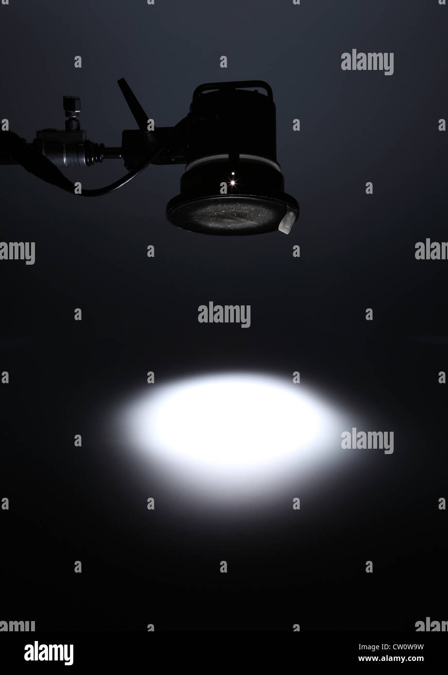 A photographic light from above creating a white spotlight on an empty dark background. Stock Photo