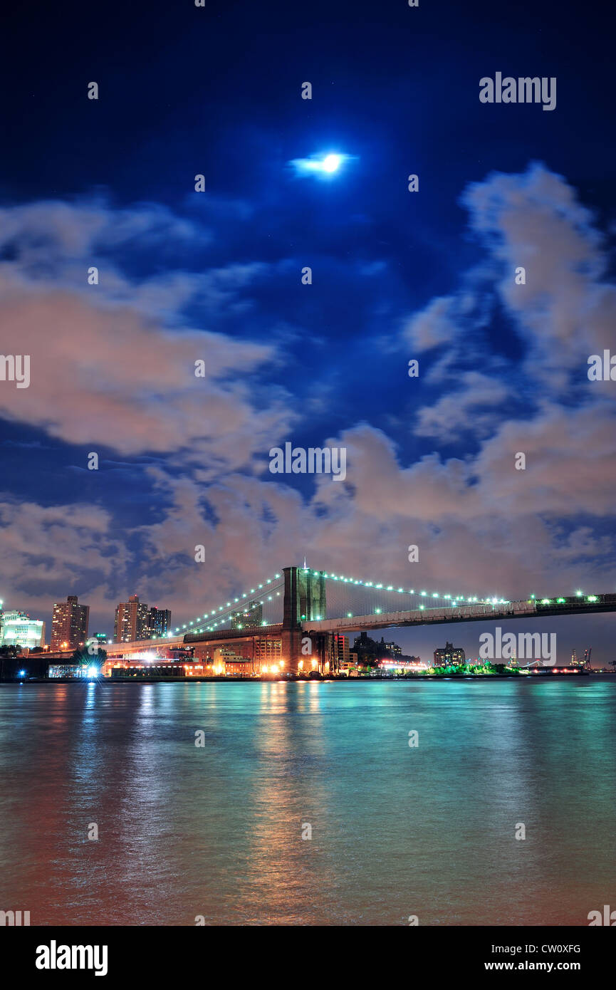 Brooklyn Bridge over East River at night with moon in New York City