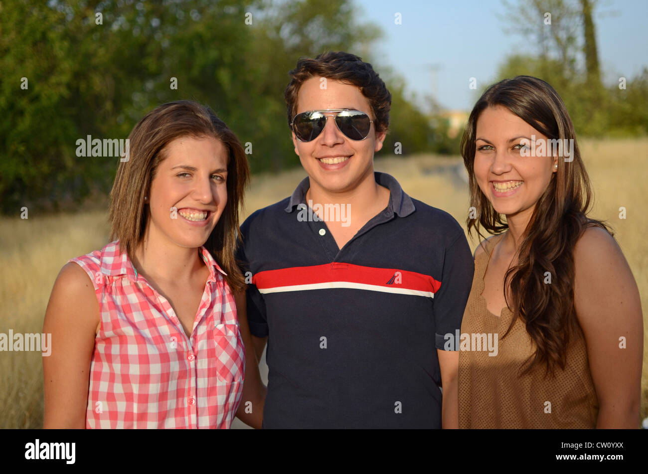 Two young women and a young man posing in nature Stock Photo - Alamy