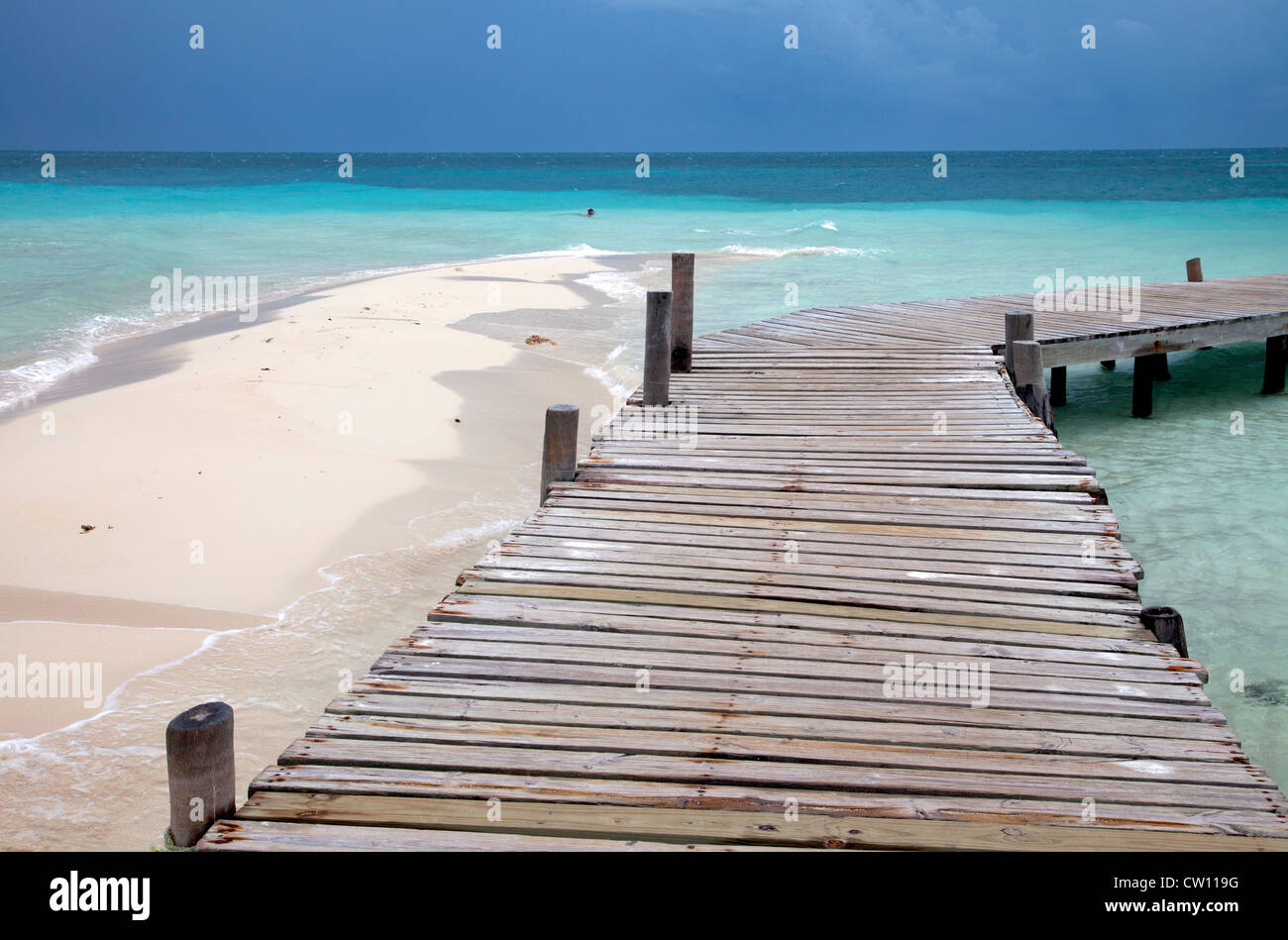 A rickety dock stretches out into turquoise water off Goff's Caye in Belize. Stock Photo