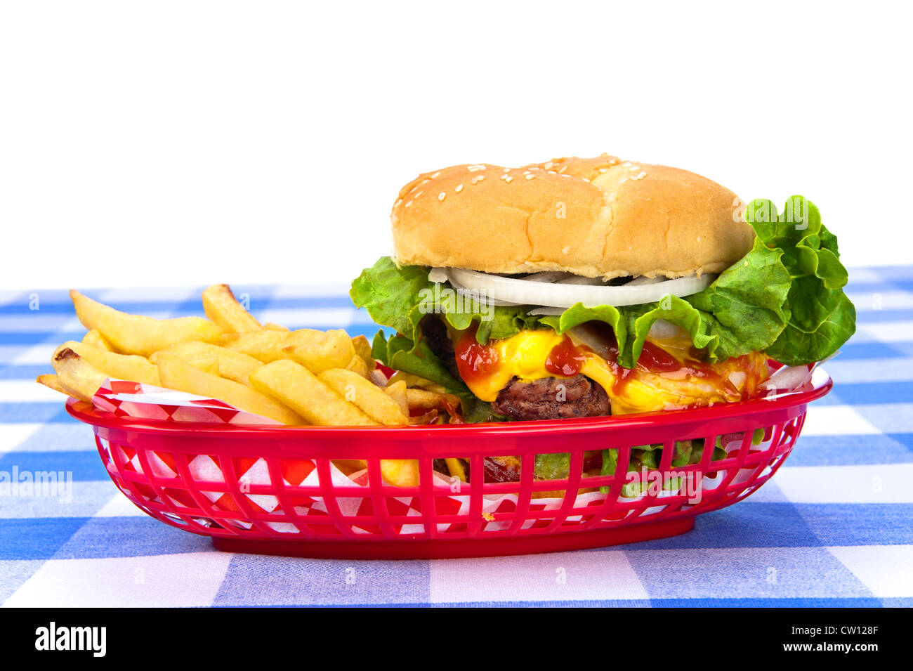 A freshly grilled cheeseburger in a red basket with freshly cooked french fries. Stock Photo