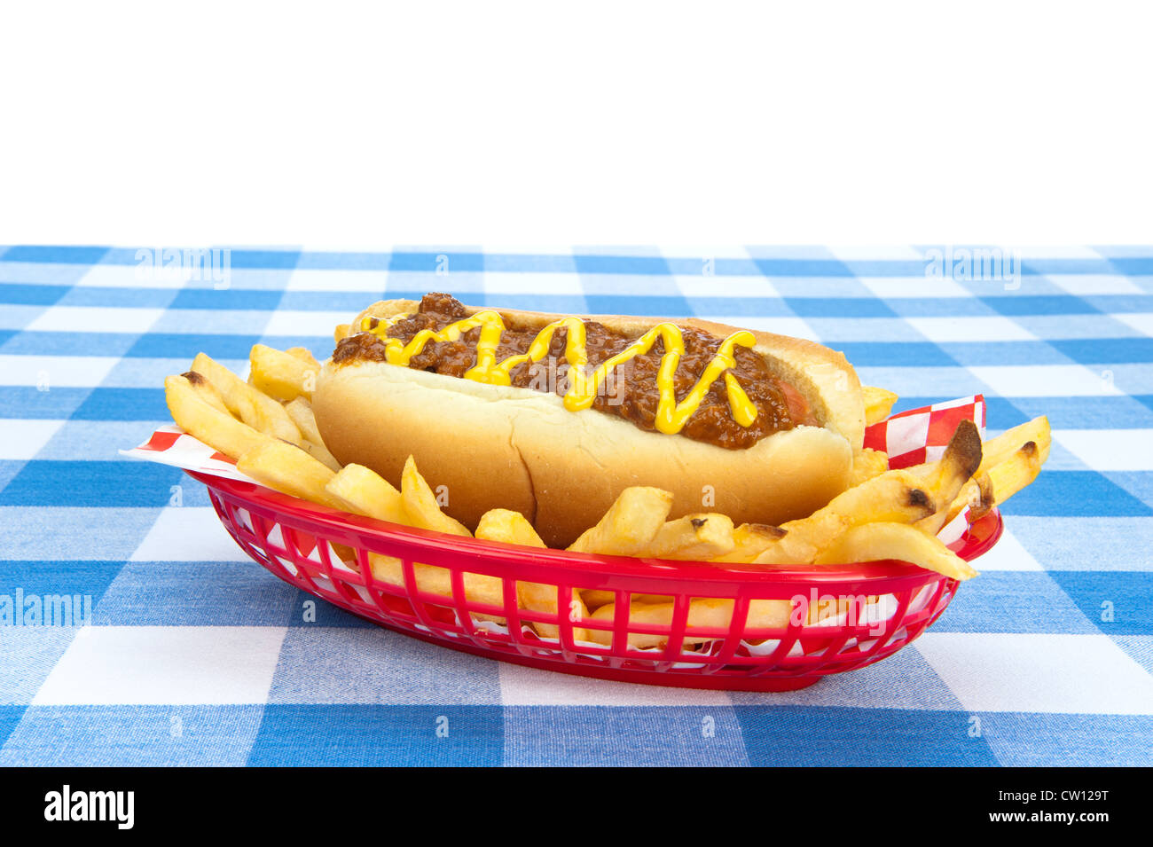 Side view of a chilidog with French fries on a checkered tablecloth. Stock Photo