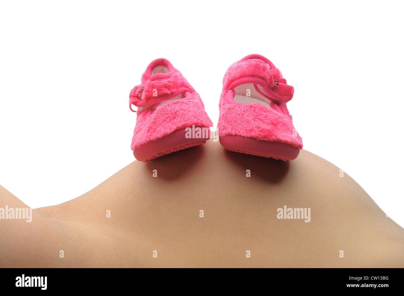 A mother lays back and rests her unborn childs shoes on her belly Stock Photo