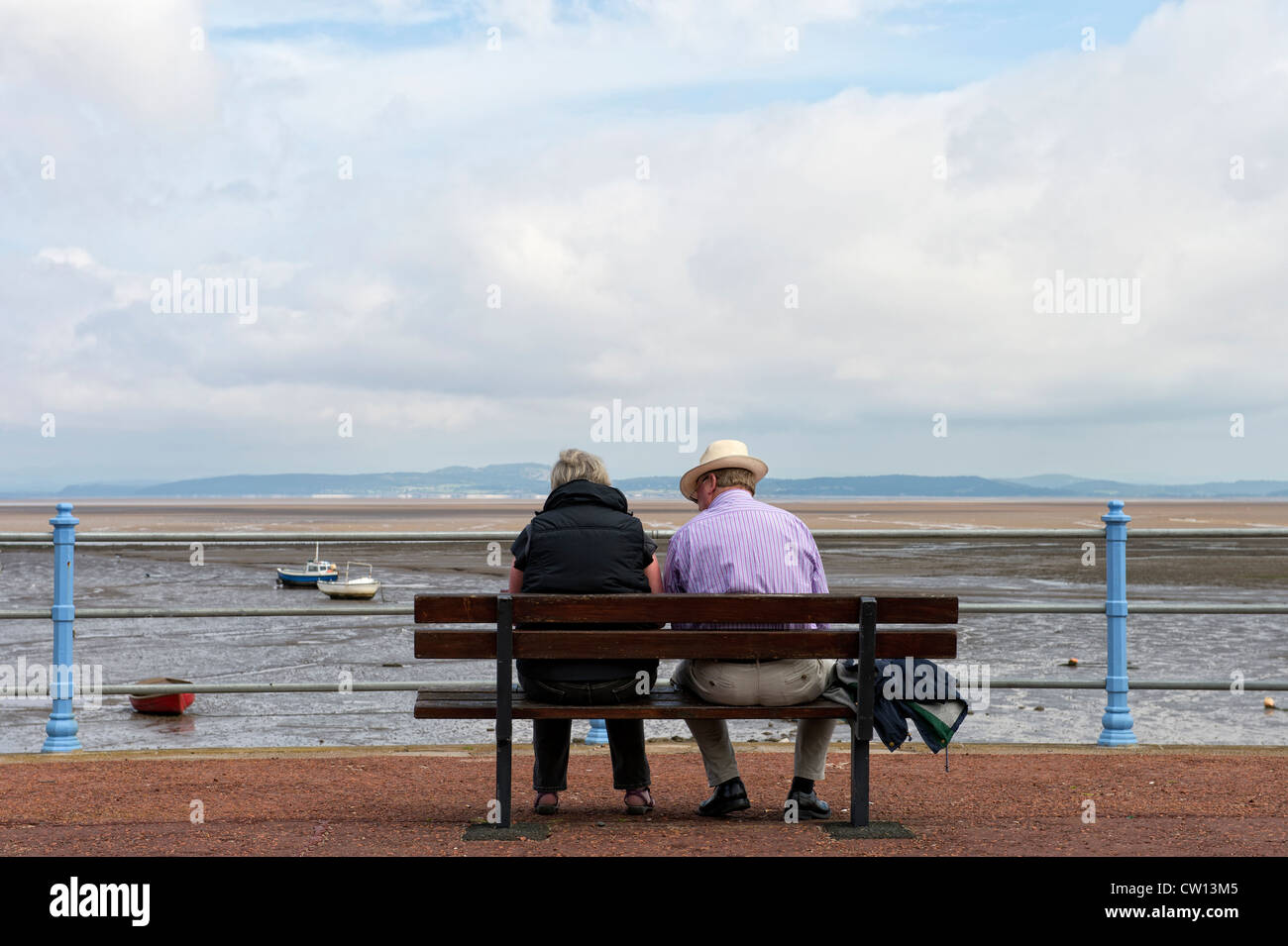 Male female couple sitting on a bench looking out to sea in Morecambe ...