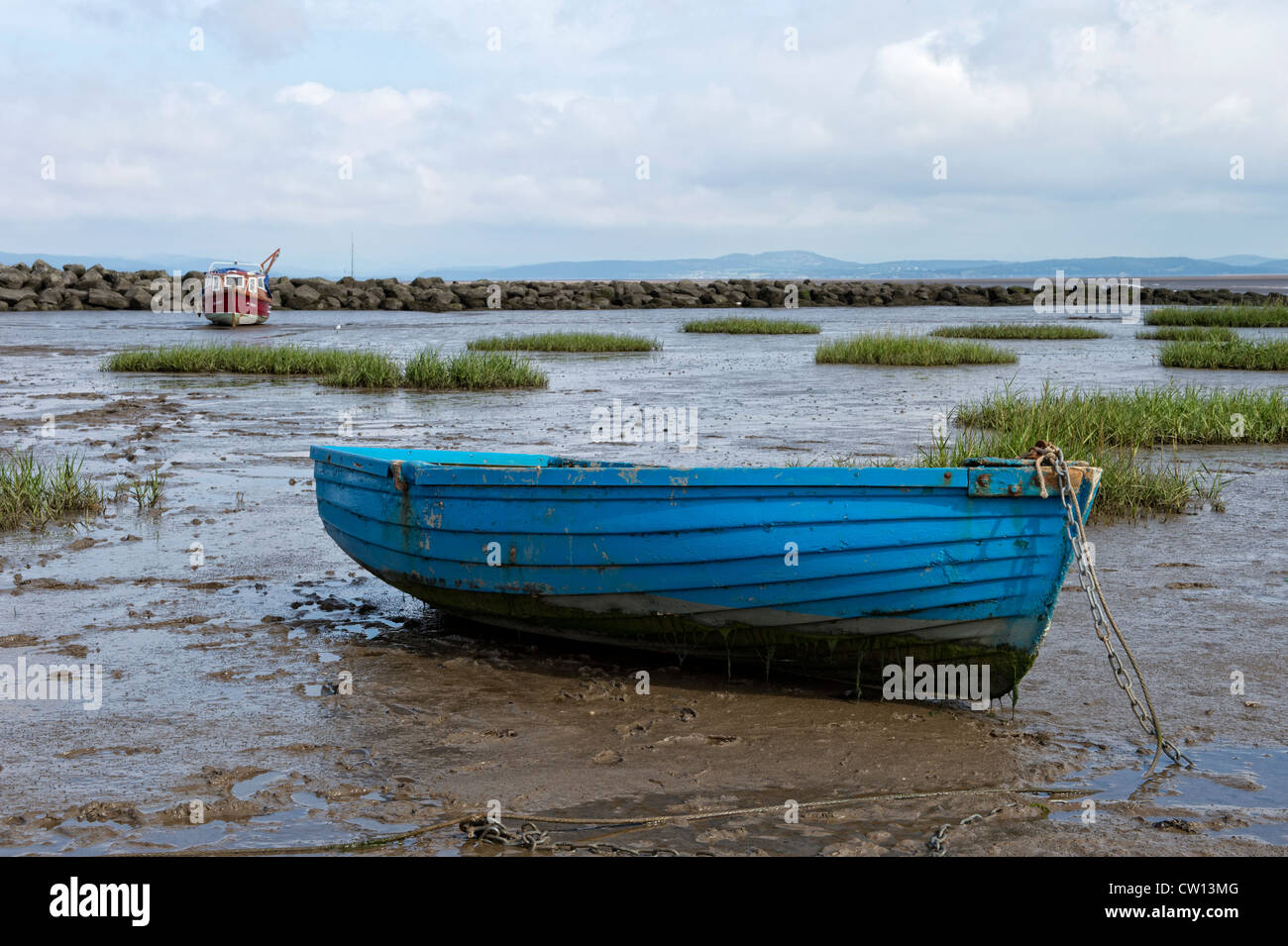 Old blue rowing boat beached by the ebb tide in Morecambe Bay, Lancashire Stock Photo