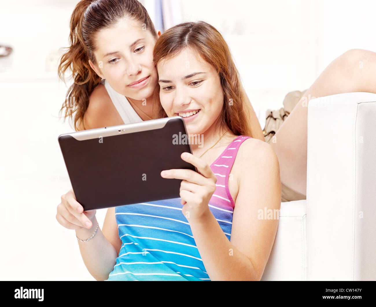 Two happy teenage girls using tablet computer at home Stock Photo - Alamy