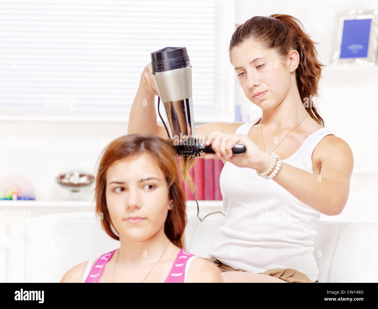 Teenage girl dries hair to her friends at home Stock Photo
