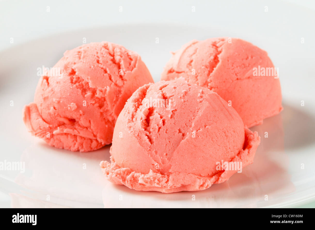 Scoops of strawberry ice cream on plate Stock Photo