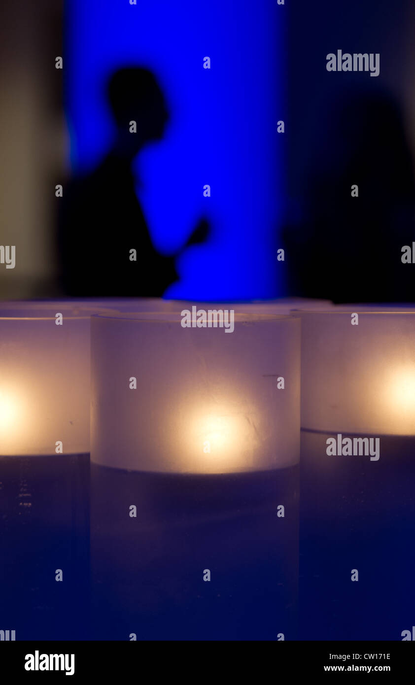 Candles with silhouette of person in background Stock Photo - Alamy
