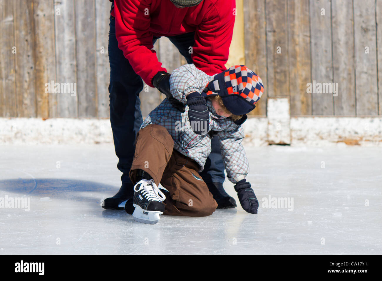 Father teaching son how to ice skate at an outdoor skating rink in winter. Stock Photo