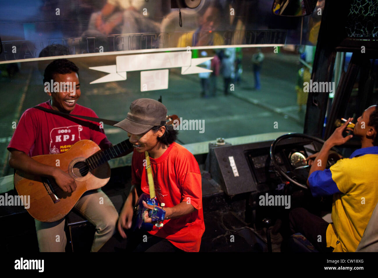 Buskers (ngamen) play music on a public bus at night in Surabaya, Indonesia. Stock Photo