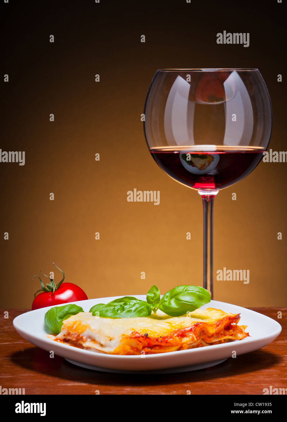 traditional lasagna with glass of red wine on a wooden table Stock Photo