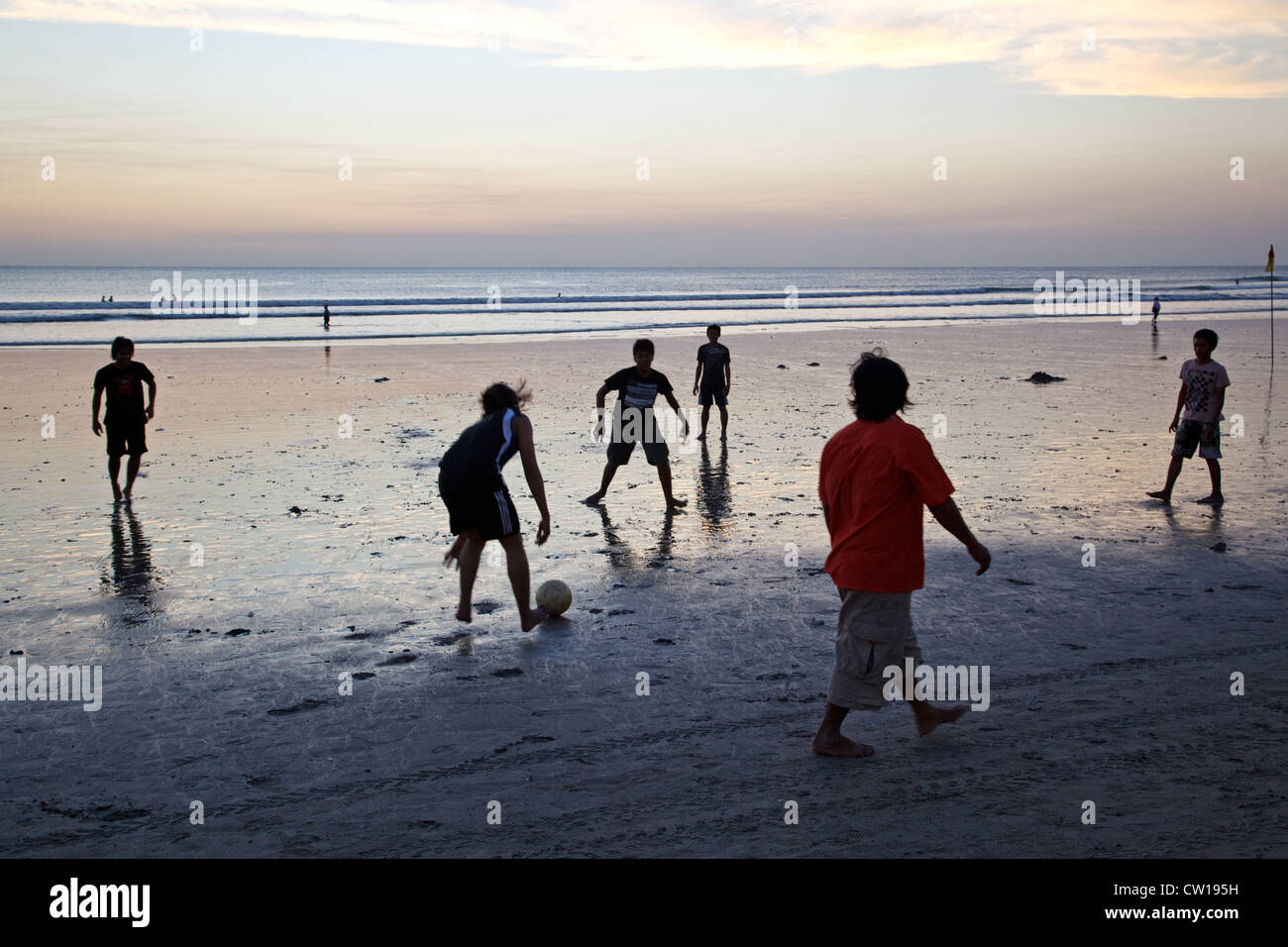 Young people play football at sunset on the beach in Kuta, Bali, Indonesia. Stock Photo