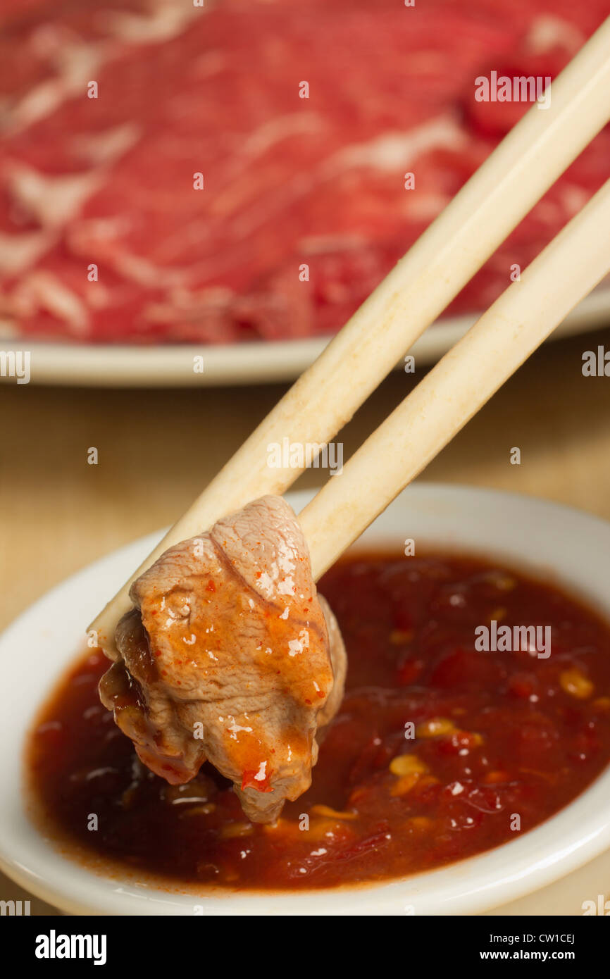 Mongolian Hot Pot, dipping cooked lamb in chili sauce Stock Photo