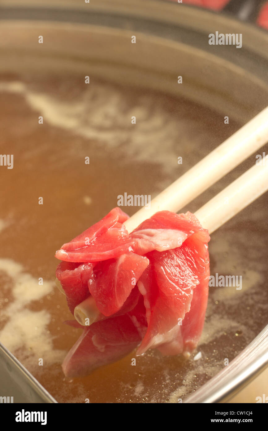Dipping lamb into a Chinese broth hotpot Stock Photo