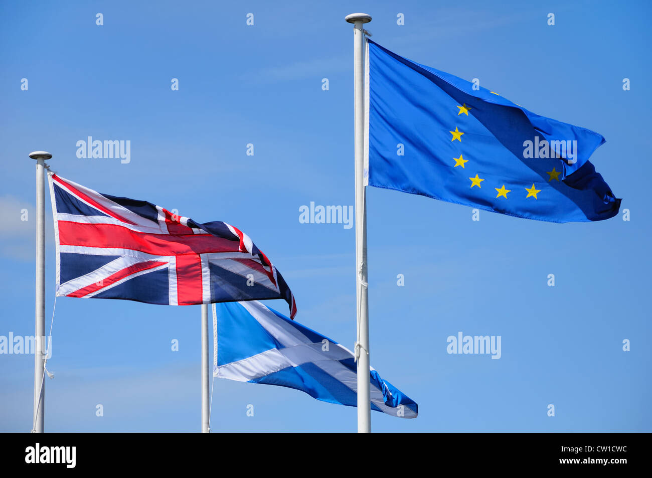 European, British and Scottish flags flying on poles in wind Stock Photo