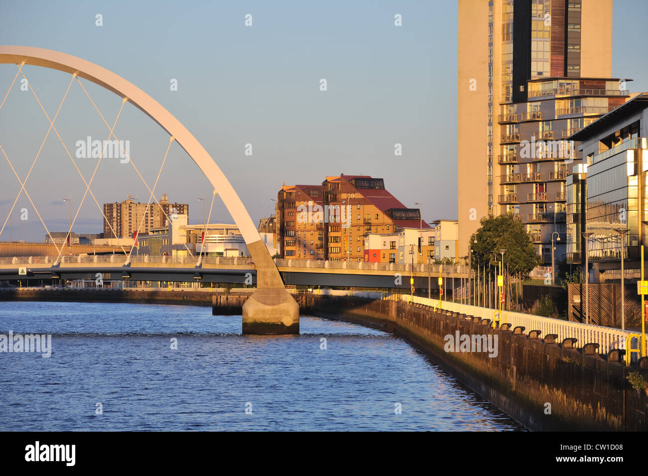 A low evening sun casts a warm glow over the river walkway in the city of Glasgow. Stock Photo