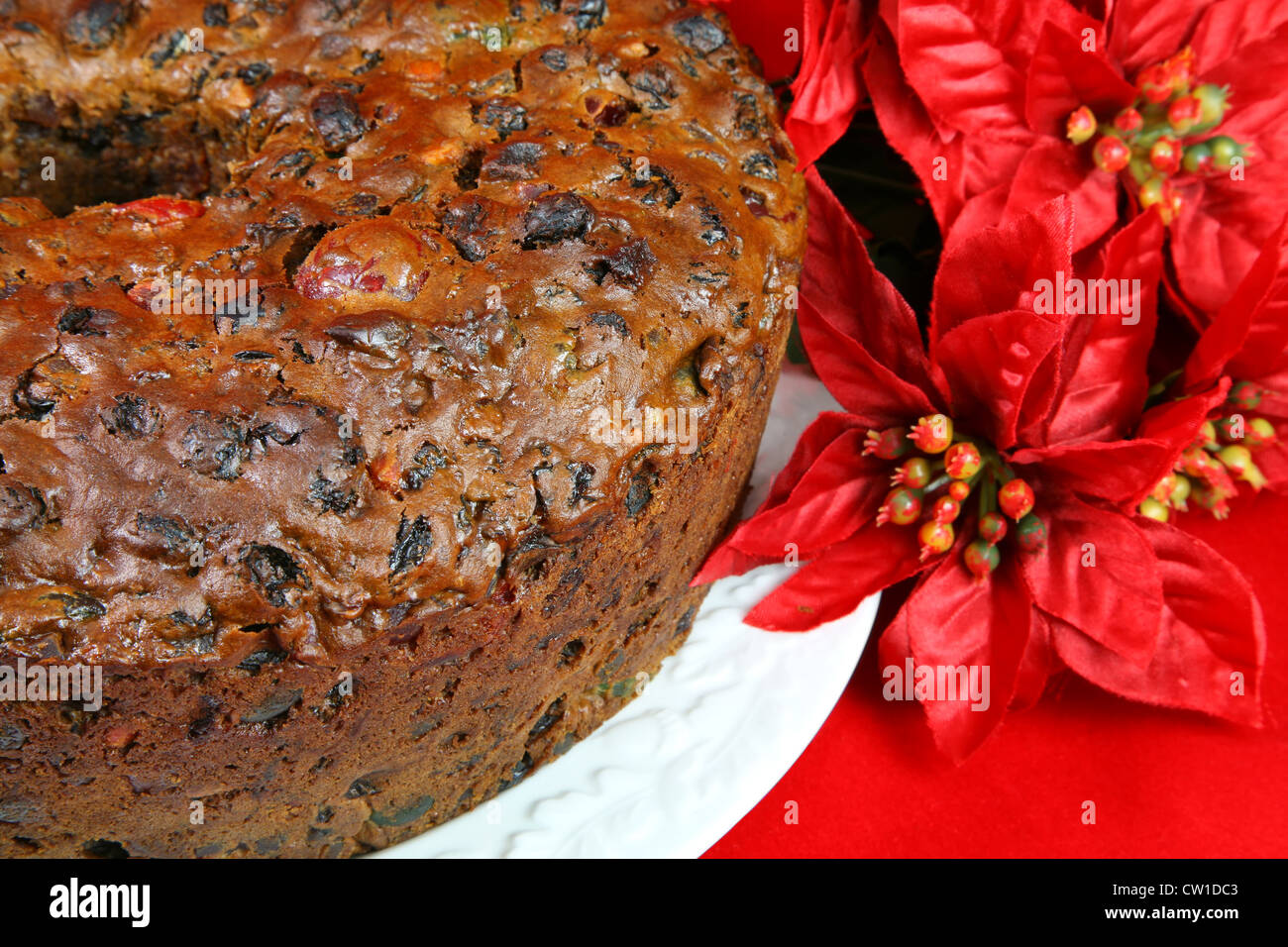 Homemade traditional Christmas fruitcake full of cherries, raisin, peel and other candied fruit. Focus is on the cake. Stock Photo