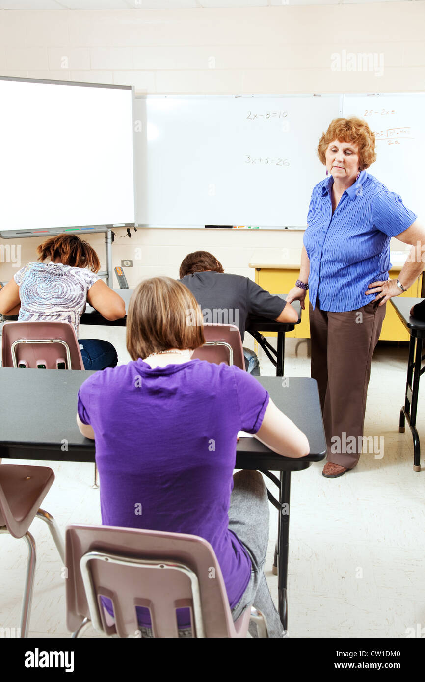 Female teacher monitoring a test in high school setting. Stock Photo