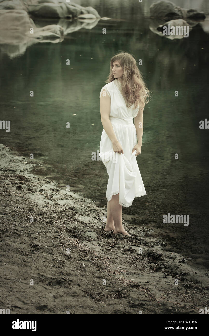 a woman in a white dress stands on a lake Stock Photo - Alamy
