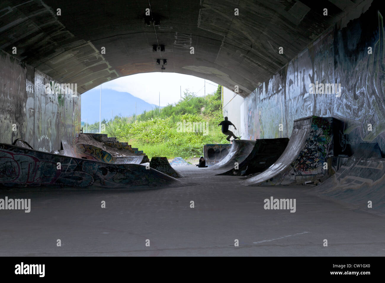 Silhouette of a skate boarder doing tricks inside a covered skate park near the Pacific National Exhibition grounds. Stock Photo