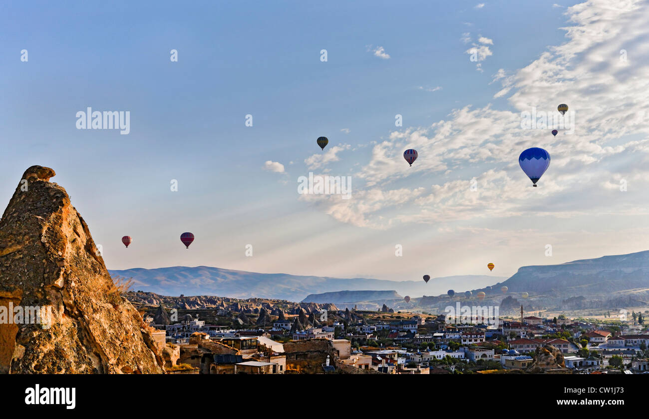 Early morning scene over the Goreme Valley in Cappadocia, Turkey. Drifting hot air balloons cut through the sun rays Stock Photo