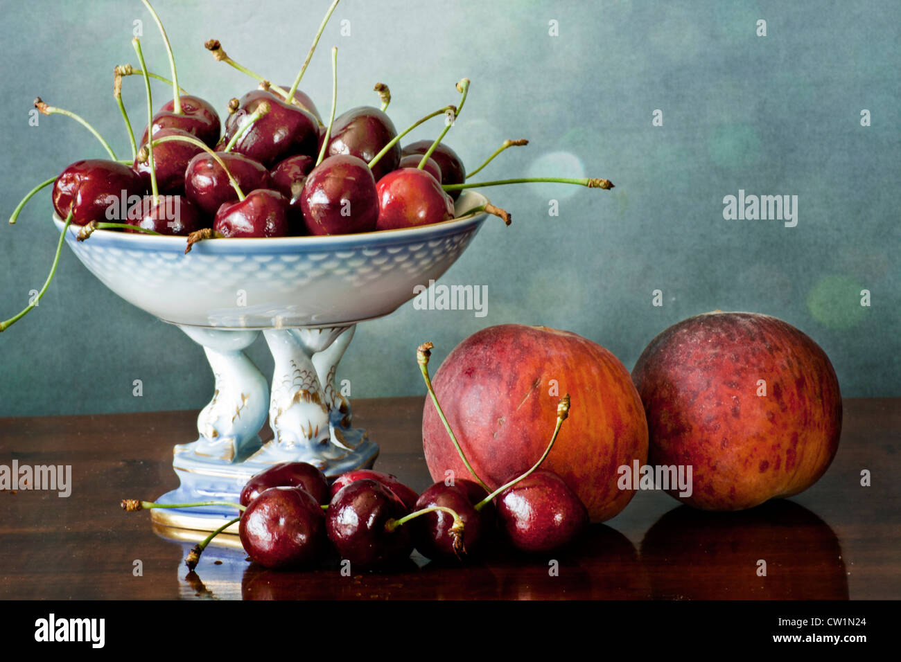 Interior with dark red cherries on a china tray and peaches on a wooden polished table Stock Photo