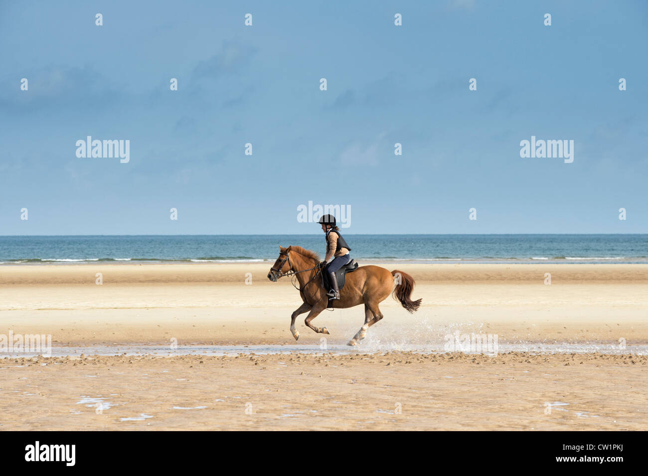 Child riding a horse on an empty beach. Wells next the sea. Norfolk. England Stock Photo