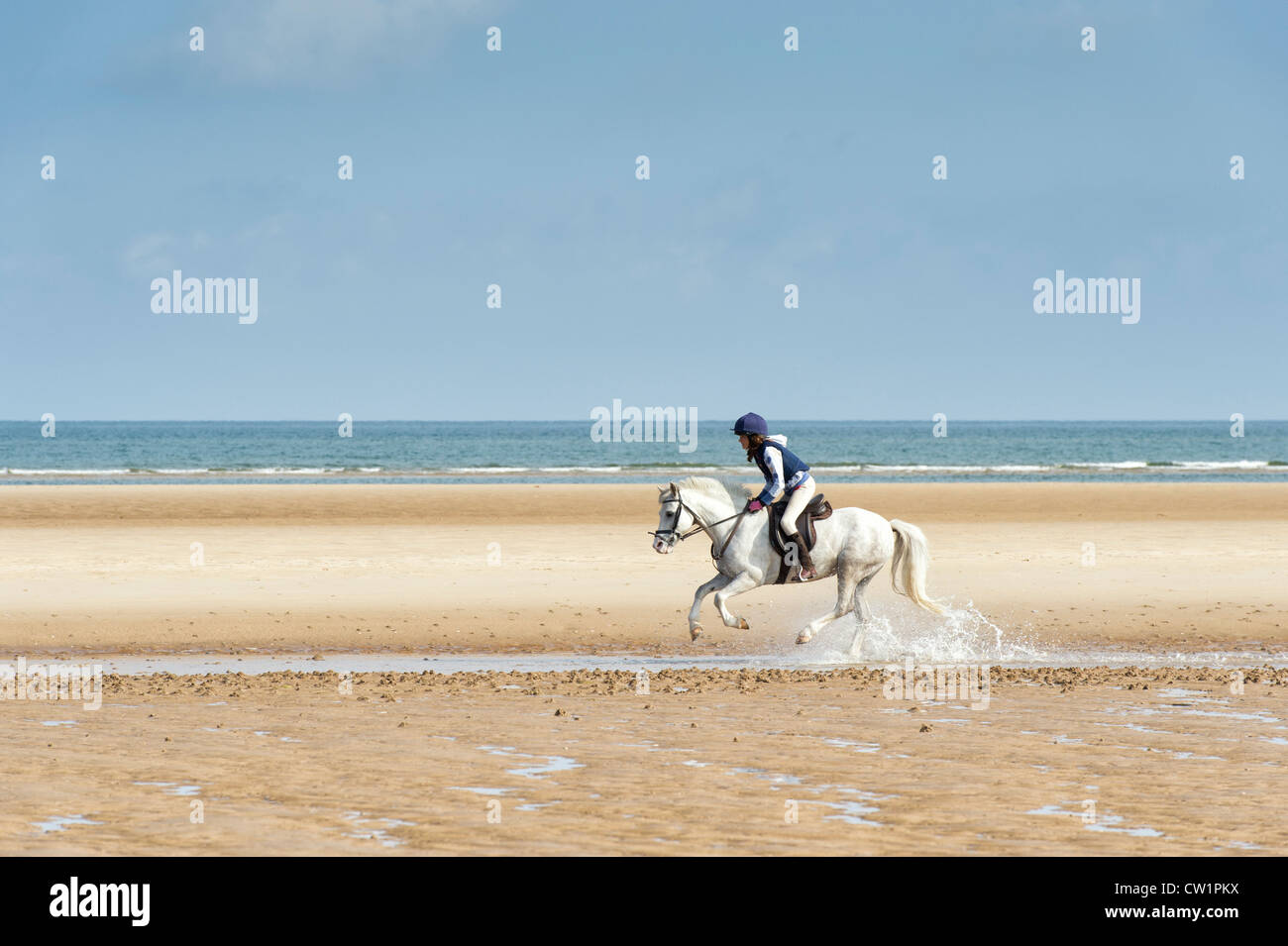 Child riding a horse on an empty beach. Wells next the sea. Norfolk. England Stock Photo