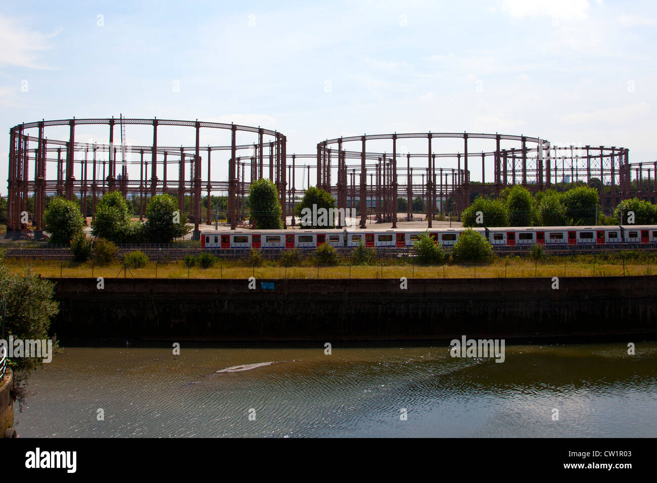 Tube train passing in front of Gasometer's of Bow gasworks, near Bow Back Rivers, Stratford, London England, UK. Stock Photo