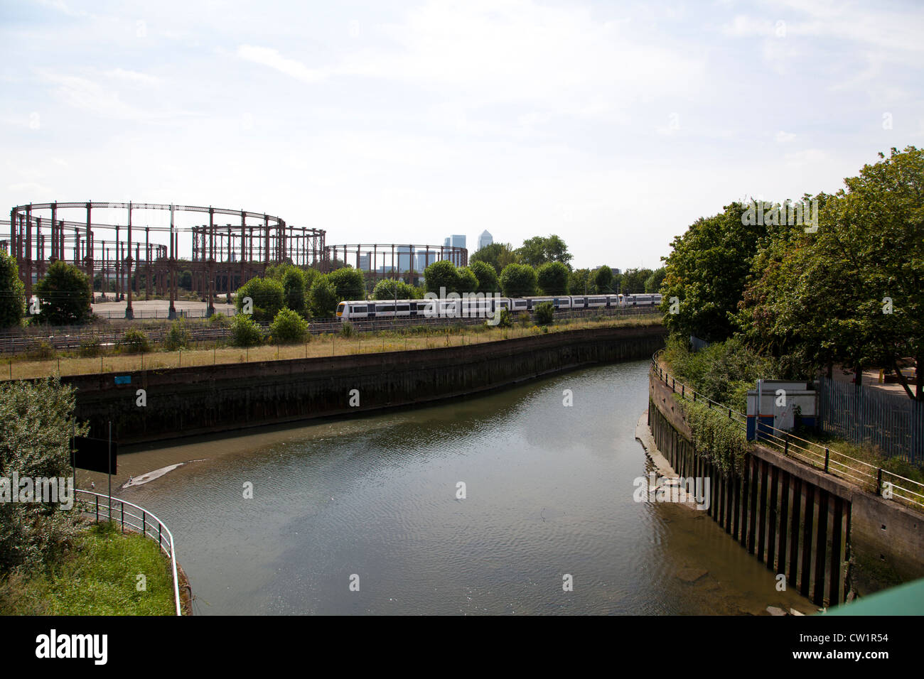 Tube train passing in front of Gasometer's near Bow Back Rivers, Stratford, London England, UK. Stock Photo