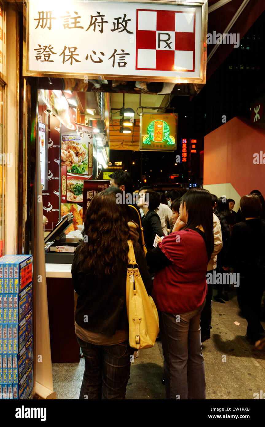 Young people queuing outside a fast food shop in Hong Kong at night Stock Photo