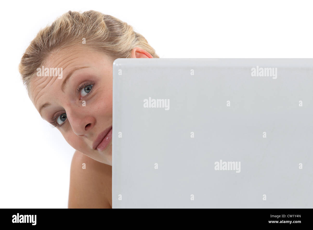 Woman peeking around a computer Stock Photo