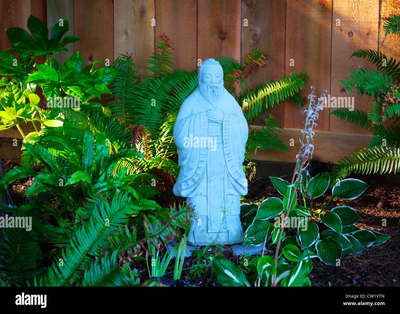 Confucius statue in sunlit garden Stock Photo