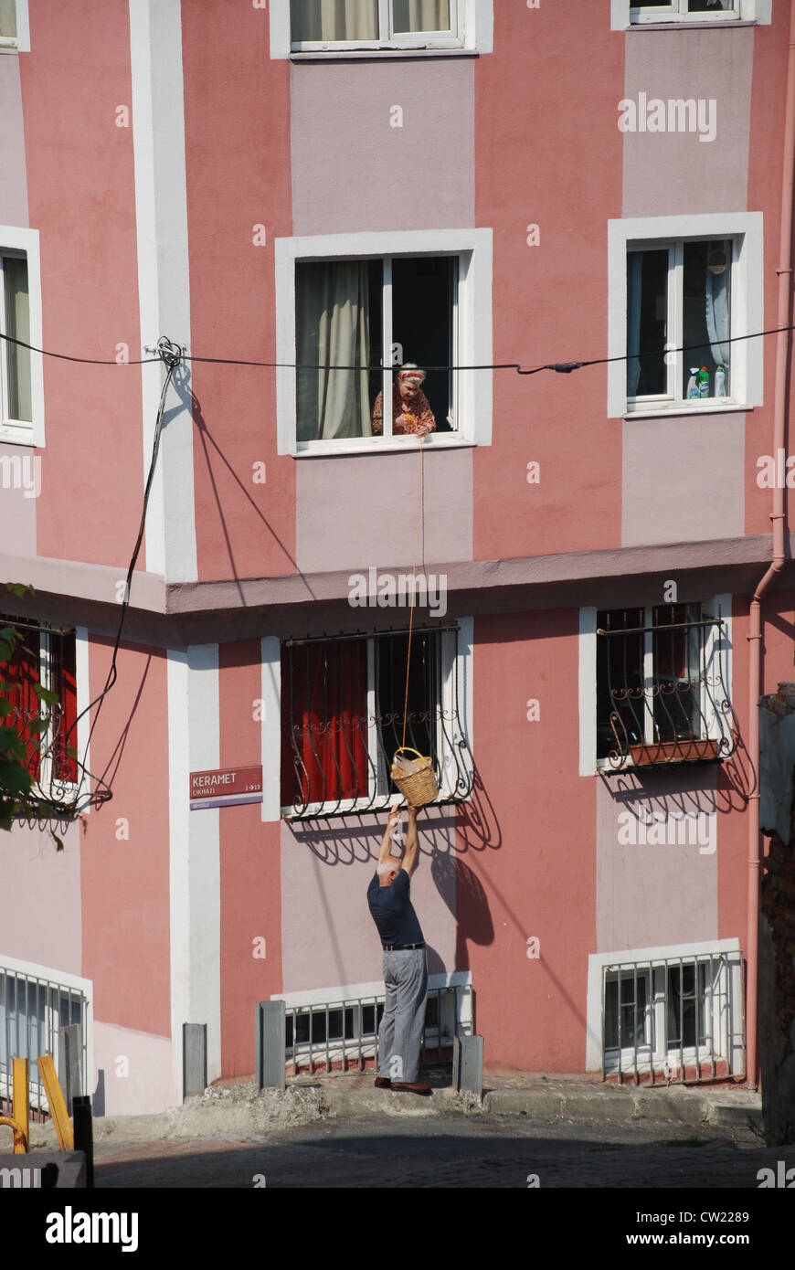 An old woman hangs a basket out of her window in the Tepebasi district of Istanbul to receive her bread. Adam Alexander/Alamy Stock Photo