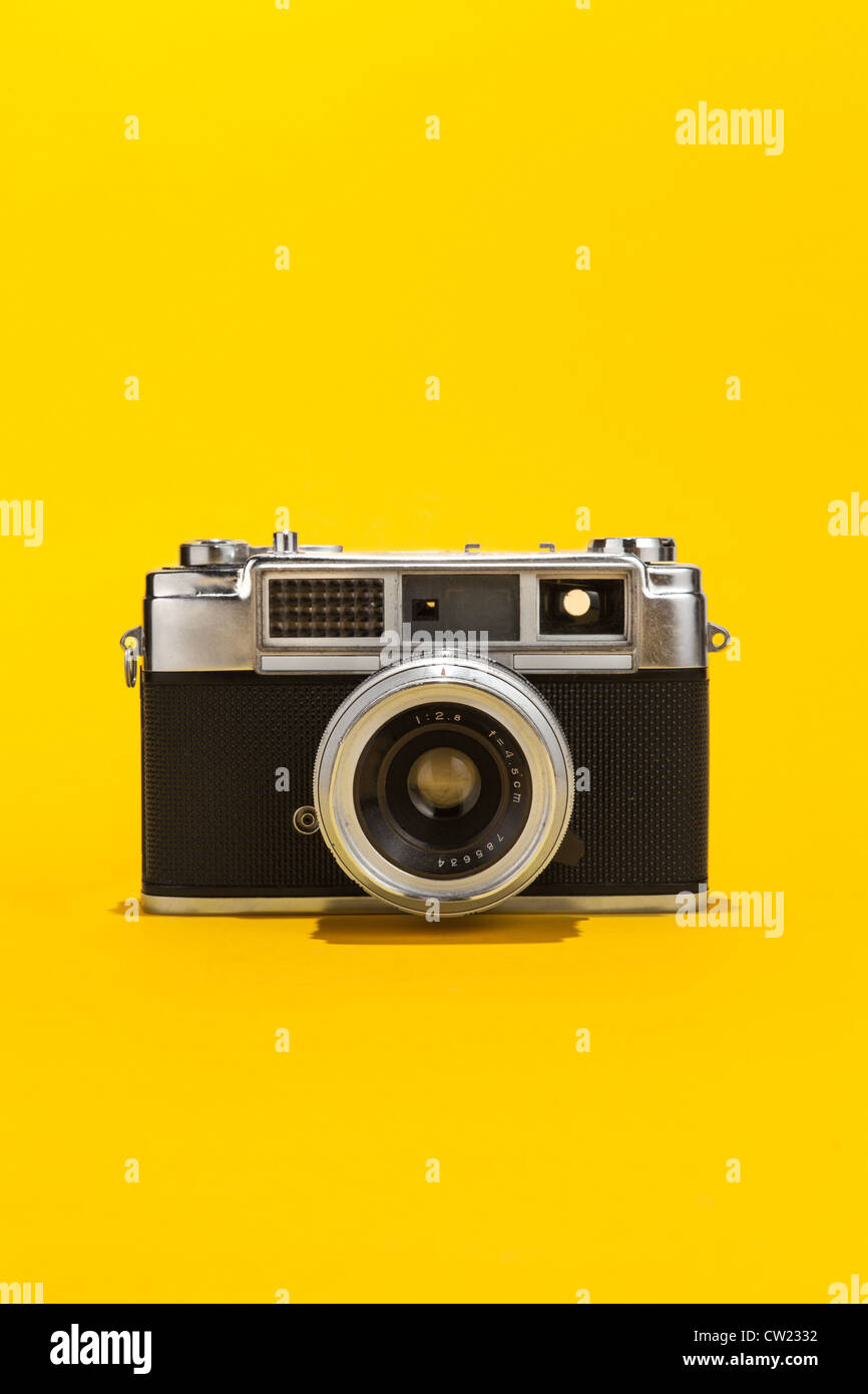 Retro analog film camera on yellow background Stock Photo