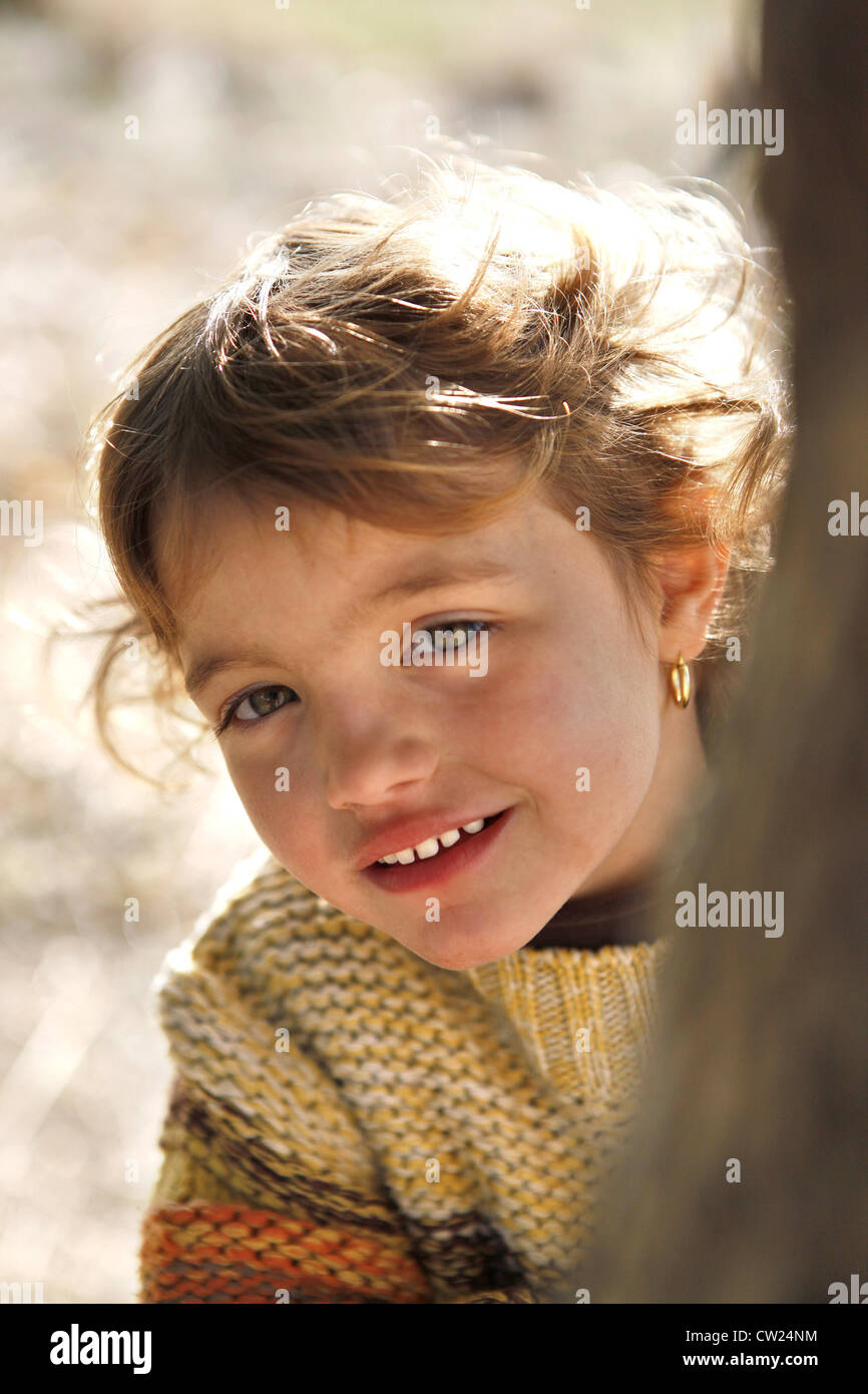 Little girl standing by tree Stock Photo - Alamy