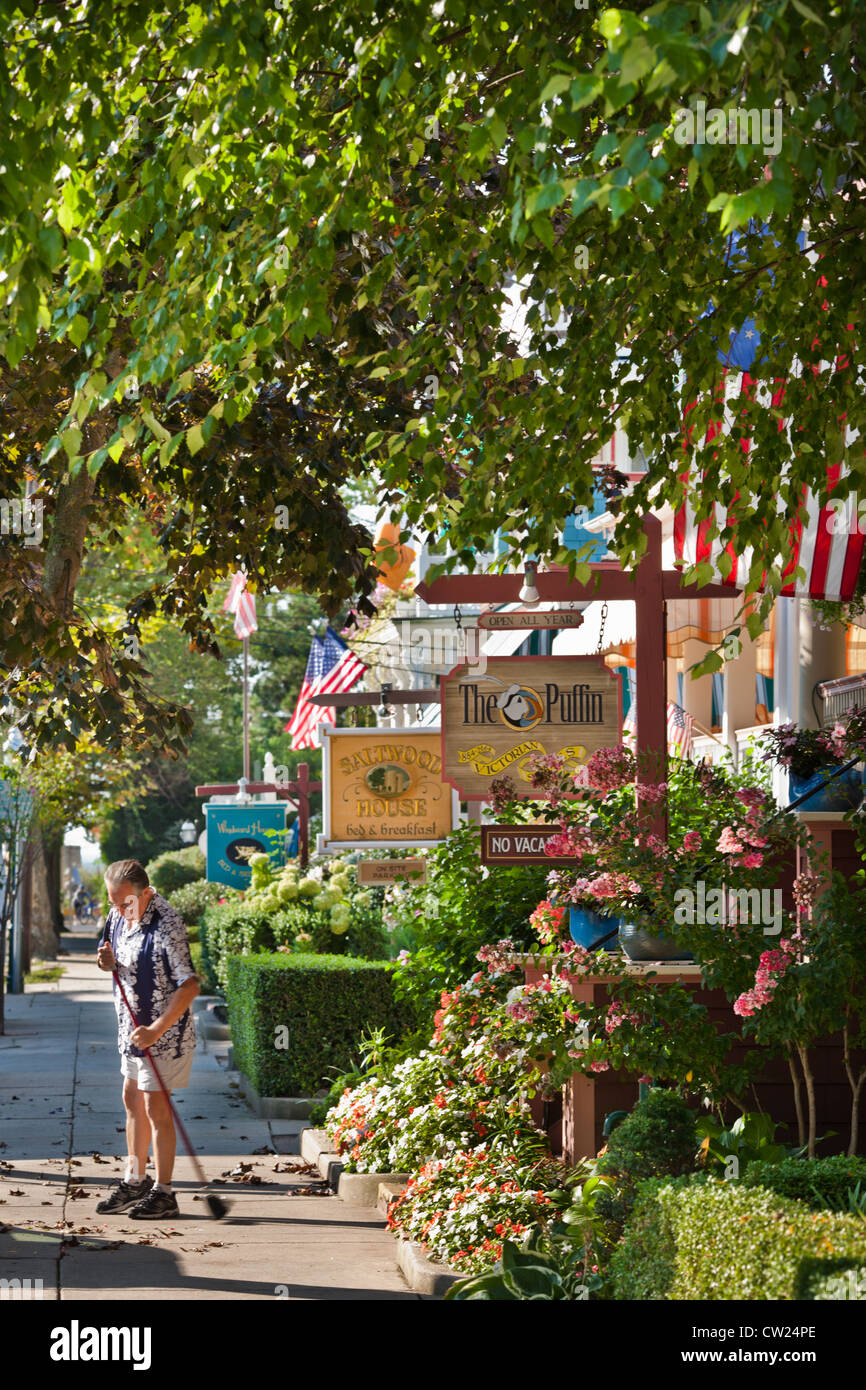 Innkeeper sweeping leaves from sidewalk in morning, Cape May, New