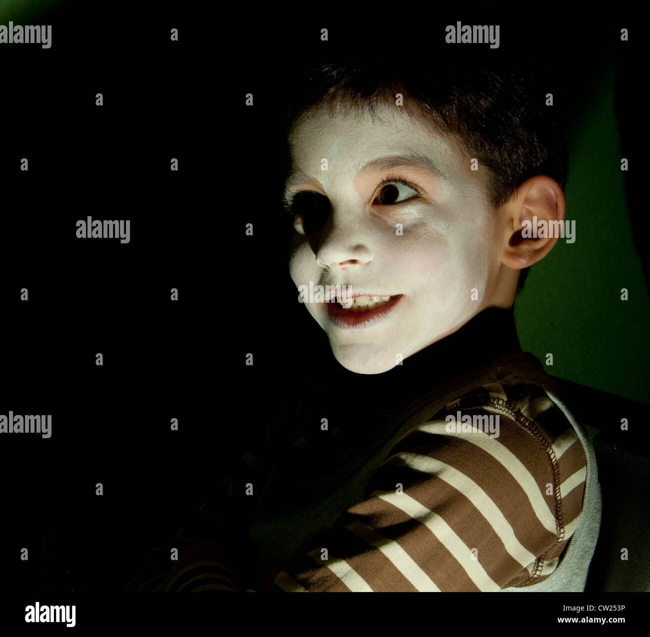 Under lit small boy in white face looking ghoulish Stock Photo
