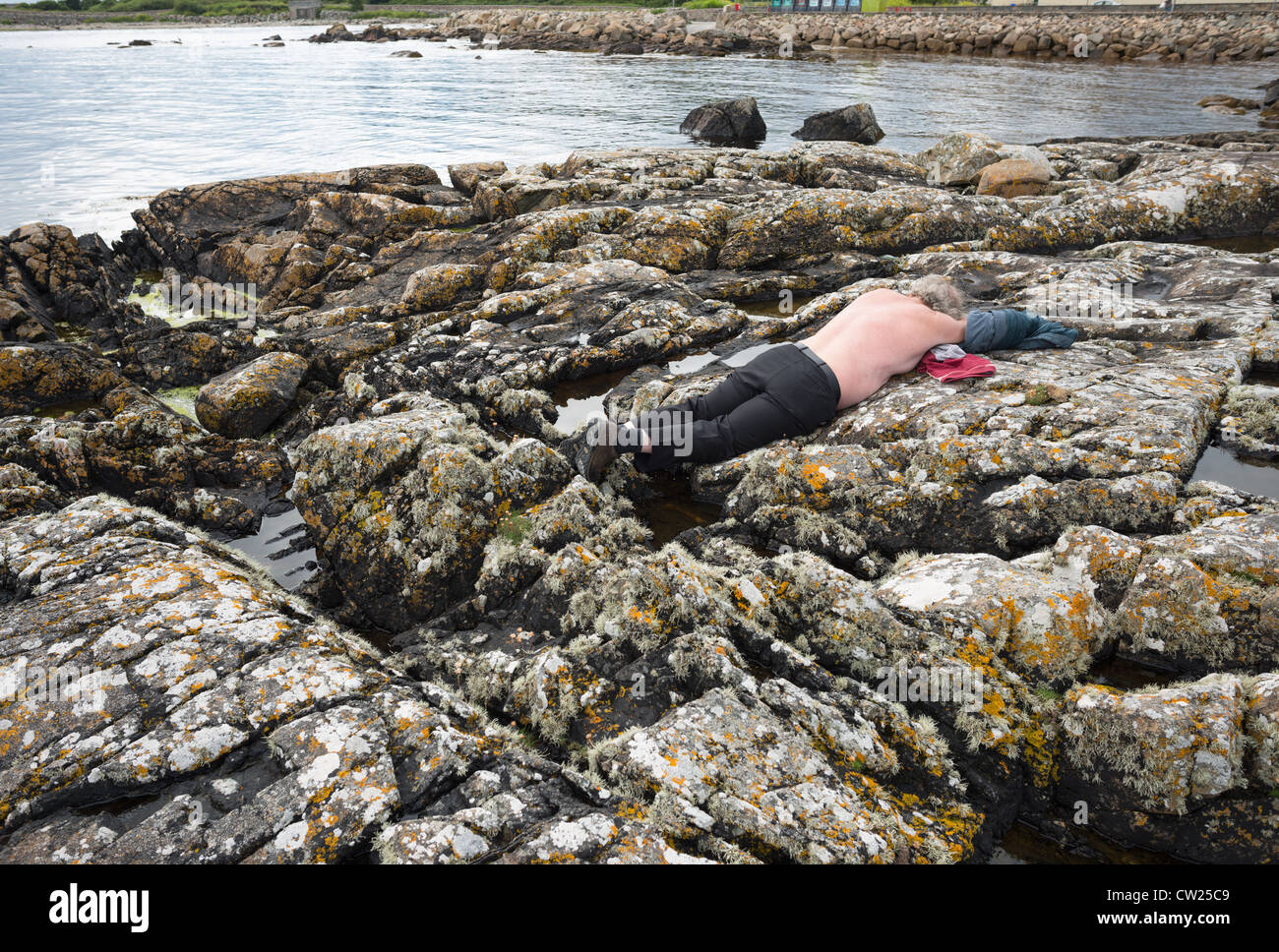 An old man taking in the sun on county Galway's south coast. Republic of Ireland. Stock Photo