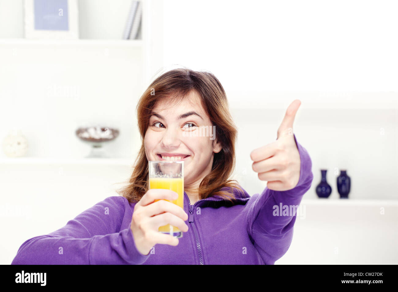 happy teenage girl drinks orange juice at home Stock Photo