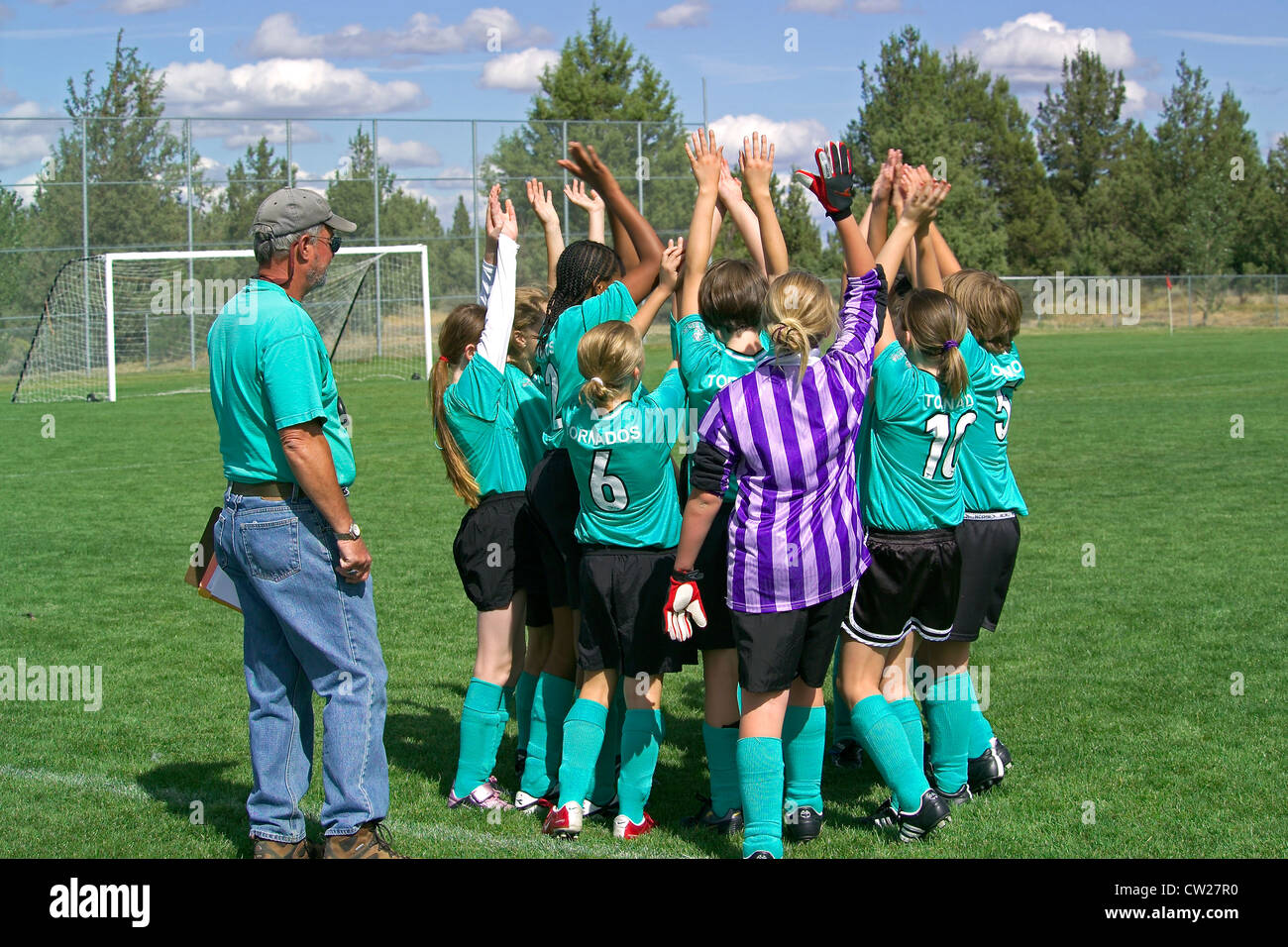 Young girls raise their hands in the air for a 'high five' team salute at the start of an after-school soccer match in Bend, Oregon, USA. Stock Photo