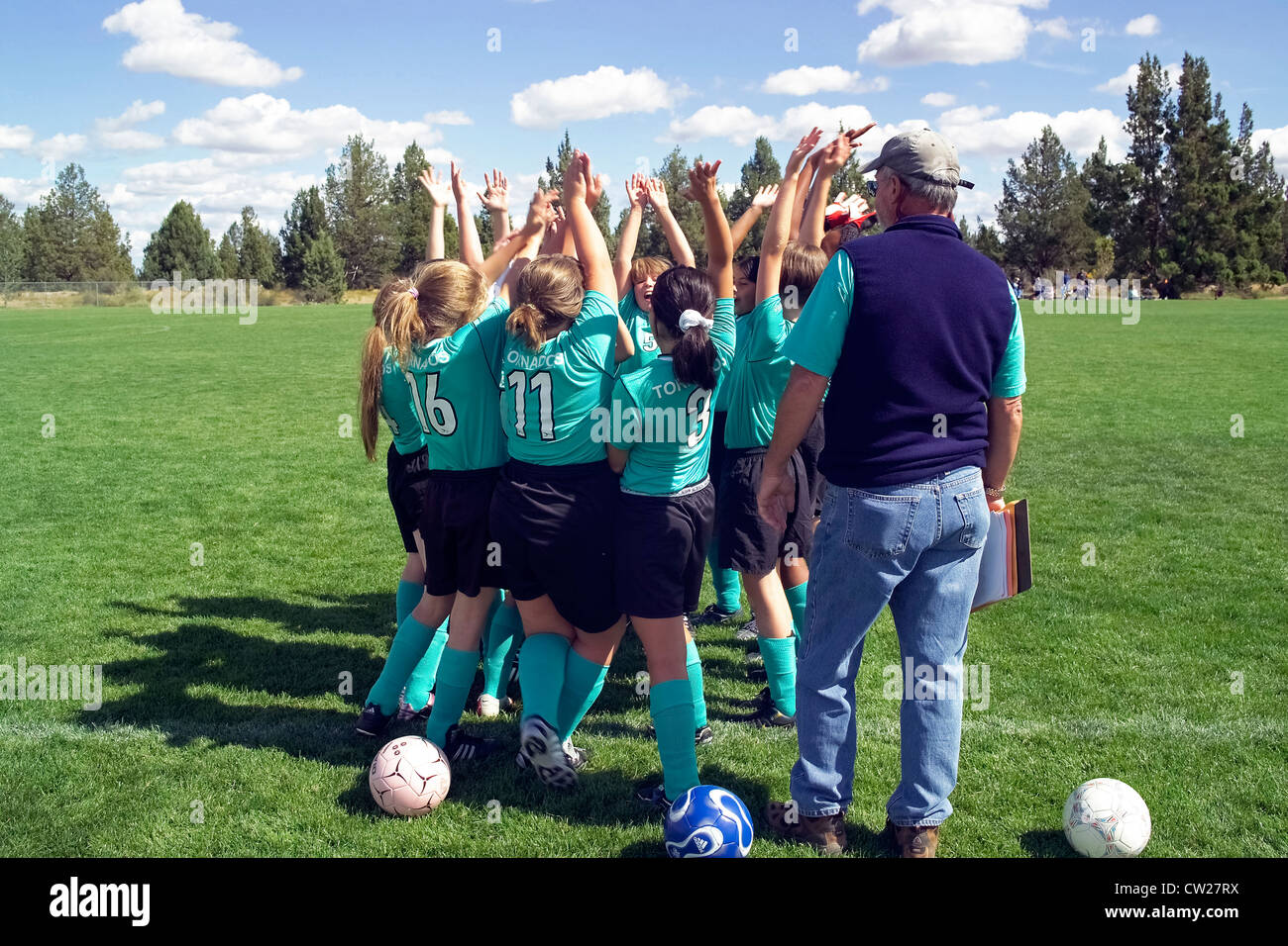 Young girls raise their hands in the air for a 'high five' team salute at the start of an after-school soccer match in Bend, Oregon, USA. Stock Photo