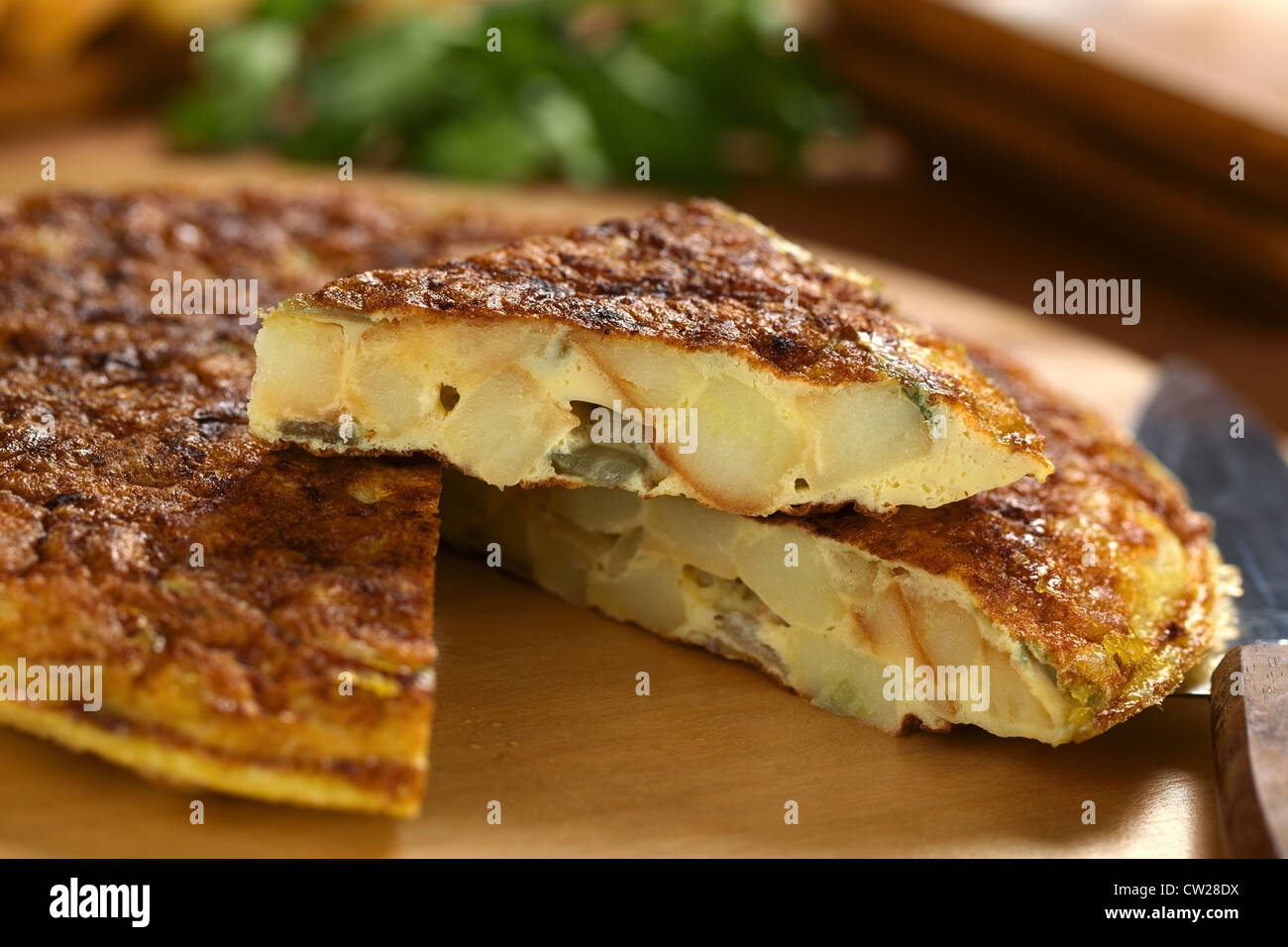 Fresh homemade Spanish tortilla (omelette with potatoes and onions) with a slice on top Stock Photo