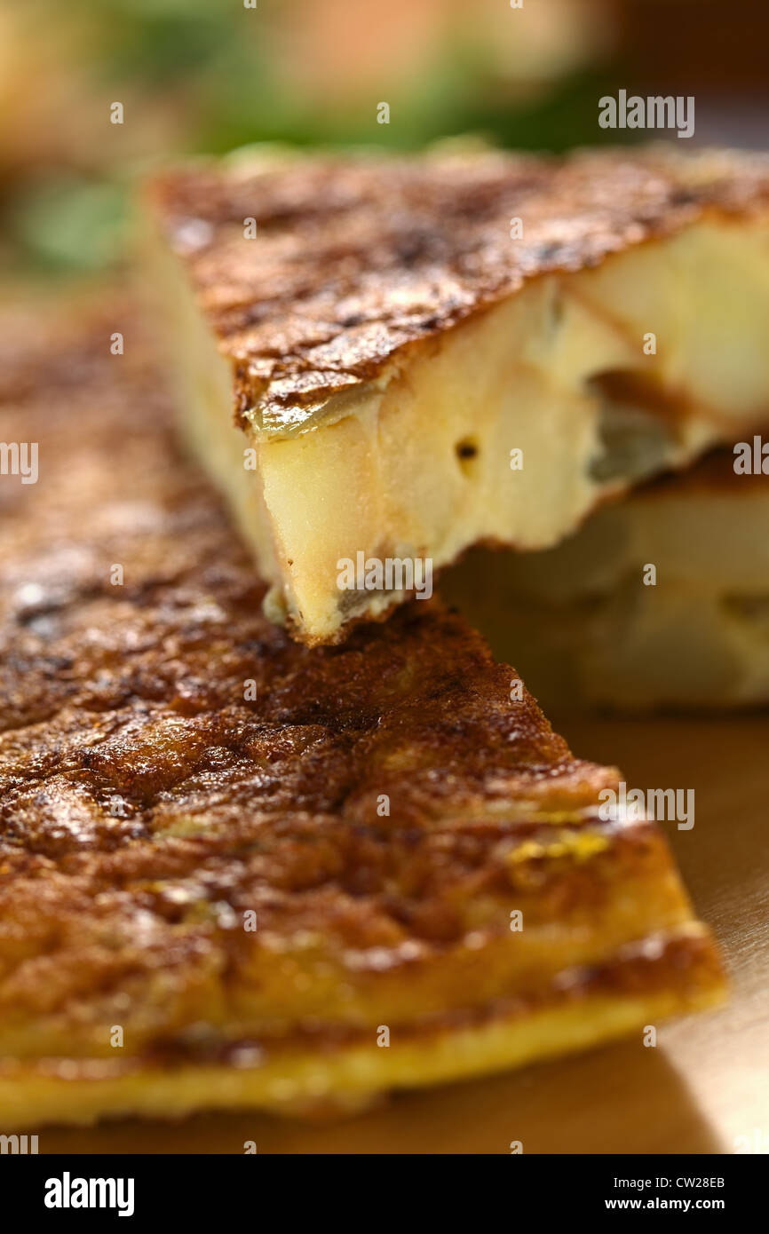 Fresh homemade Spanish tortilla (omelette with potatoes and onions) with a slice on top Stock Photo