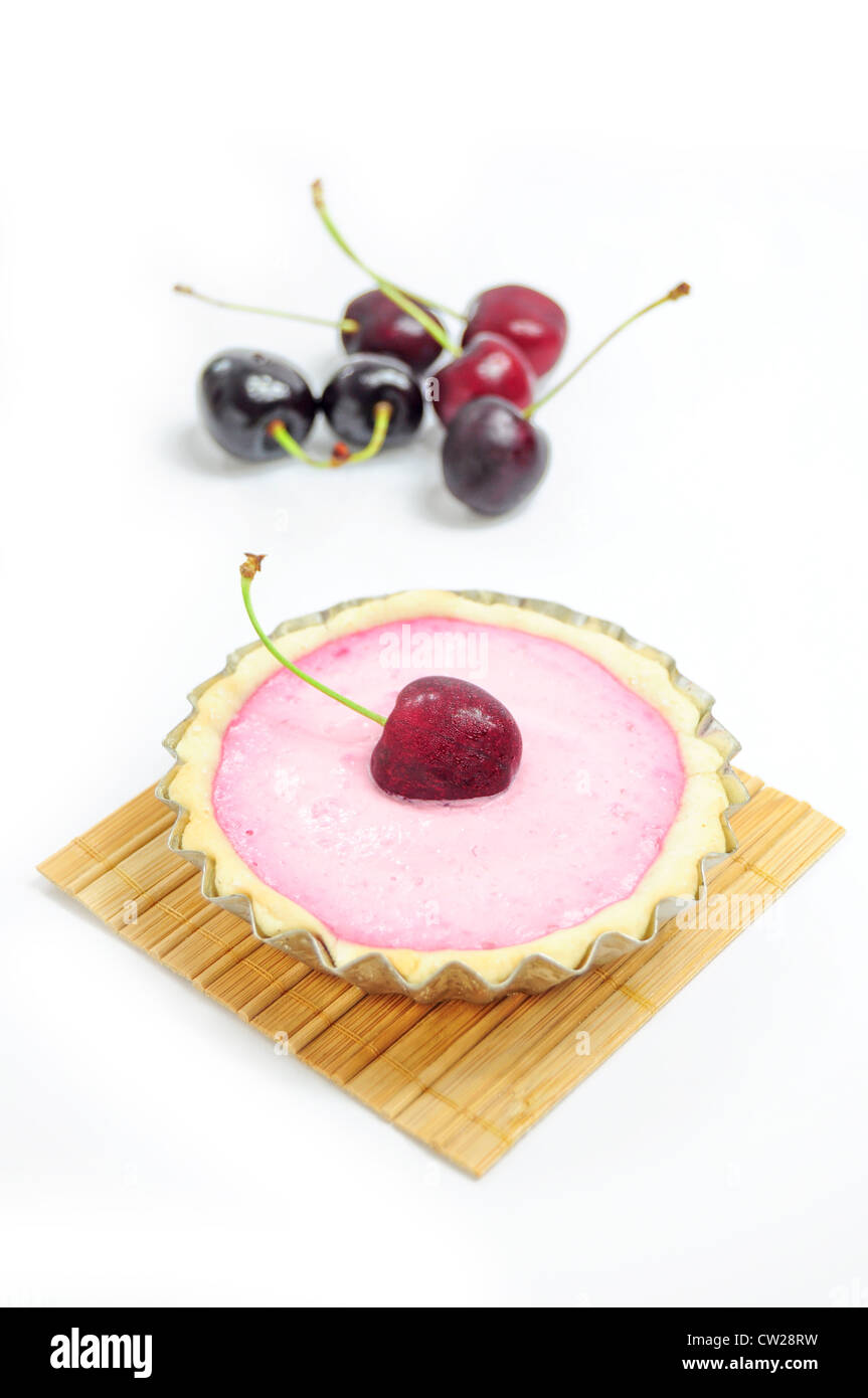 Cherry tart on wooden coaster, cherries in the background Stock Photo