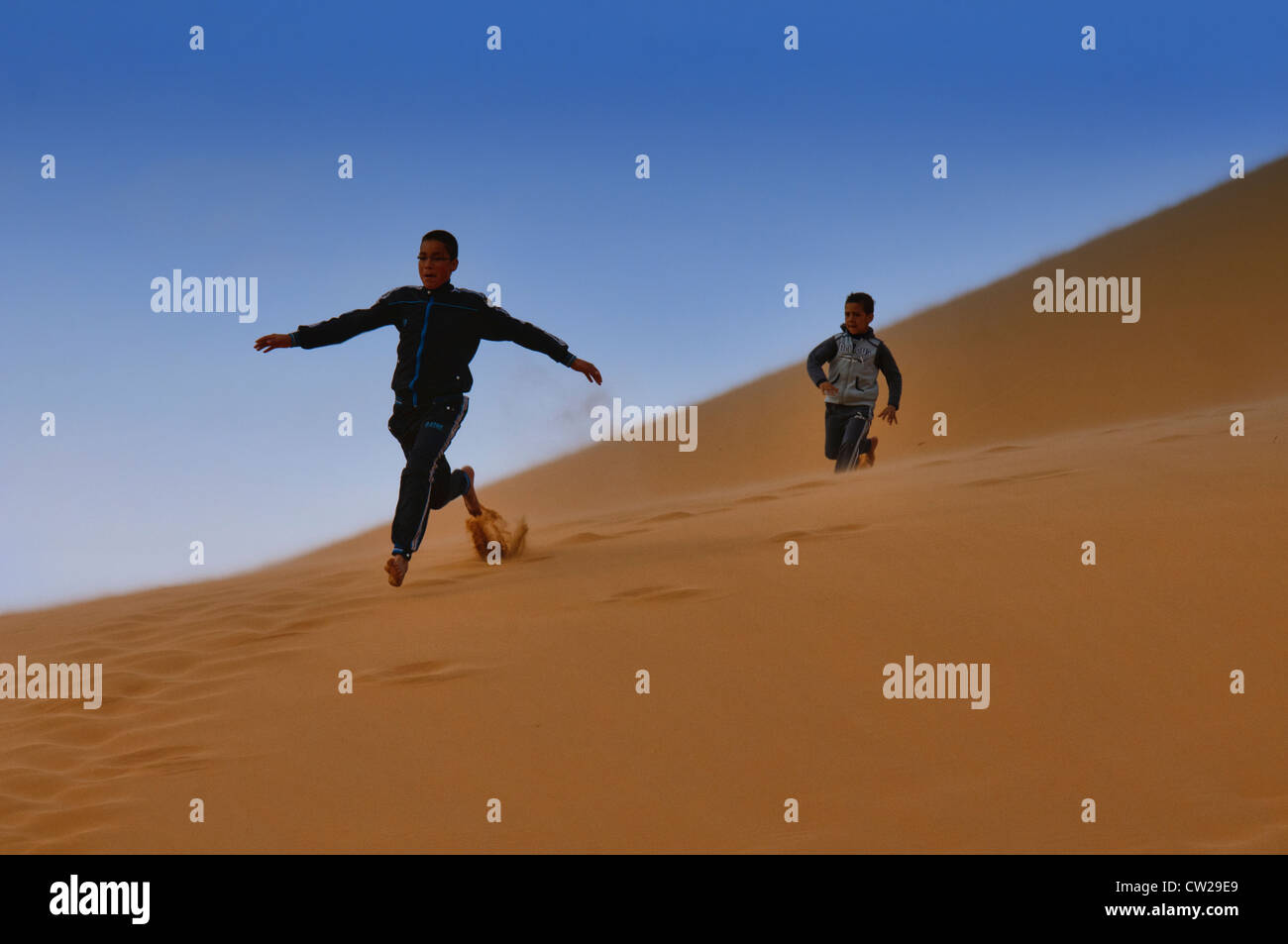 running down a sand dune in the Sahara near Merzouga, Erg Chebbi ...